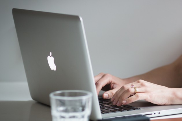 Mains sur un ordinateur portable, sur un bureau blanc